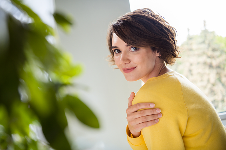 Jeune femme souriante pointant ses deux index vers son visage