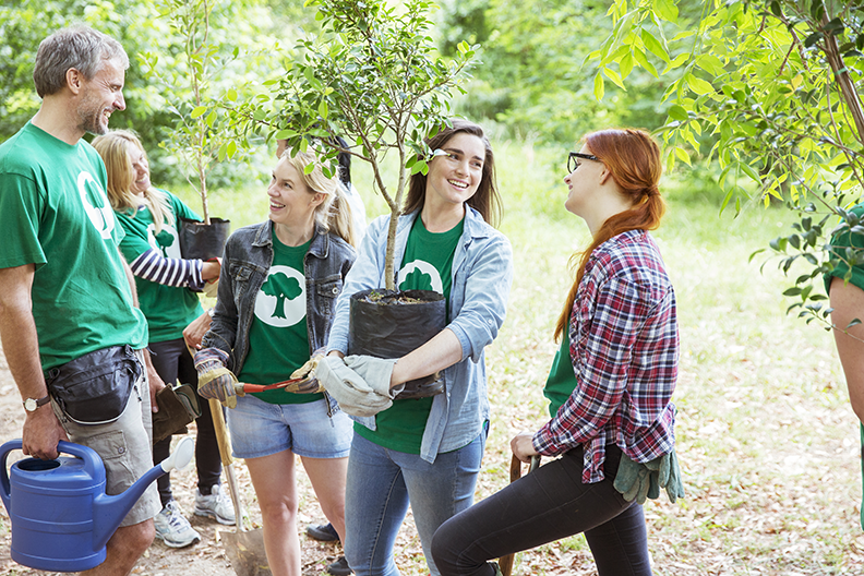 Groupe de personnes tenant des plantes et des outils de jardinage