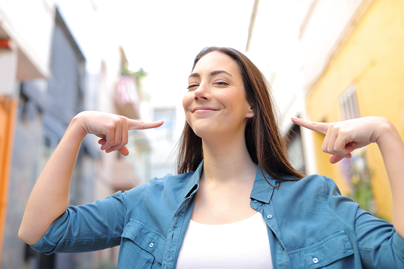 Jeune femme souriante pointant ses deux index vers son visage