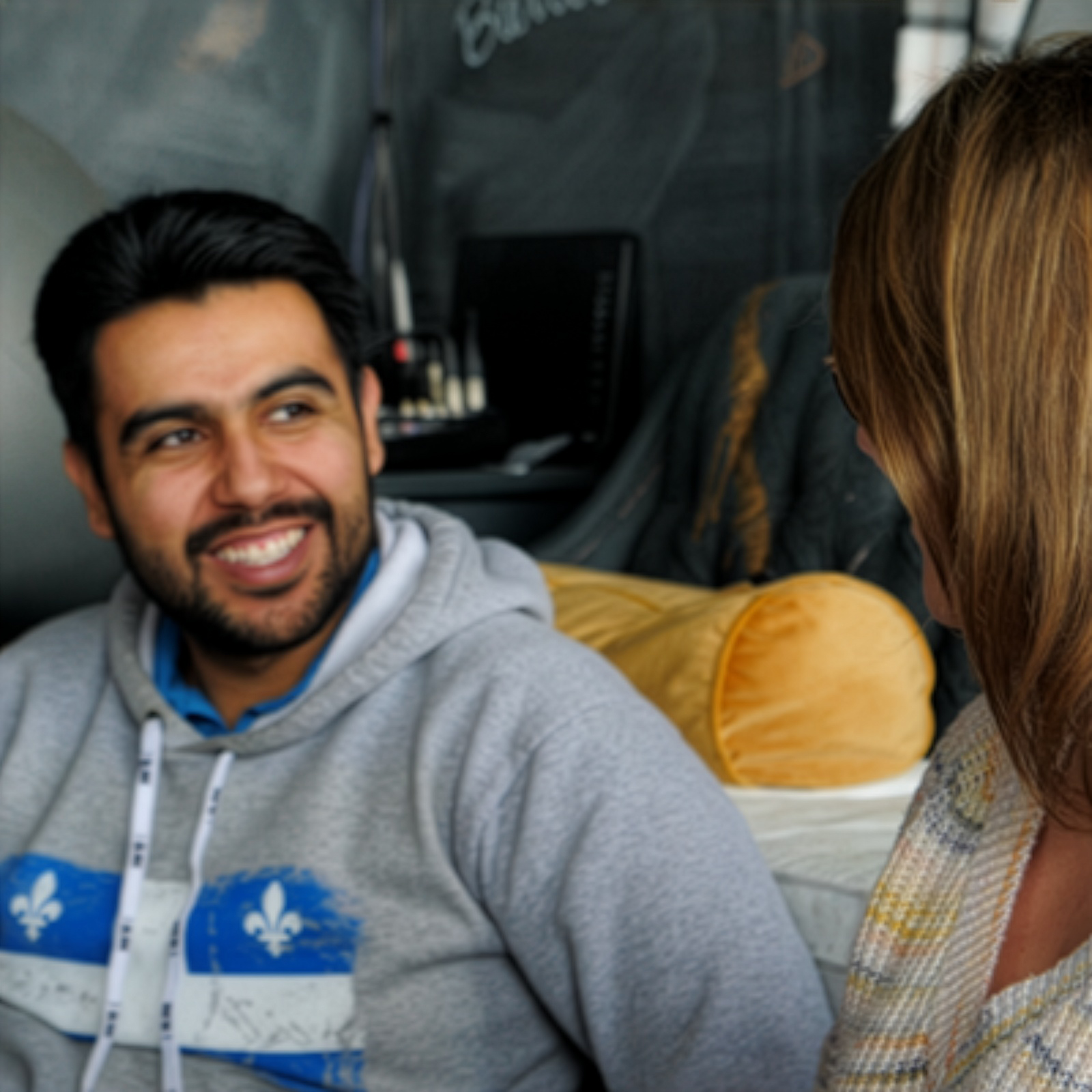 Jeune homme hispanique souriant à une jeune femme vue de profil